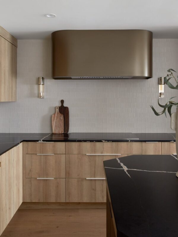 Custom wood kitchen with black countertops and brass range hood by Sunnylea Homes in Toronto.